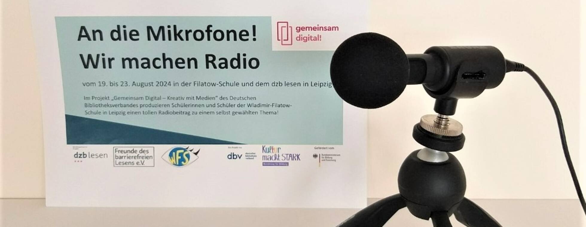 Ein Mikrofon steht vor dem Plakat zum Radioprojekt