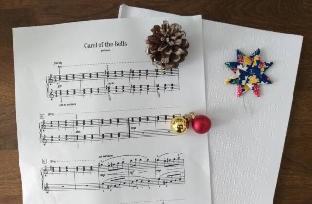 Zwei Notenblätter in Schwarzdruck und Braille von "Carol of the Bells" mit Tannenzapfen, Stern und Glöckchen