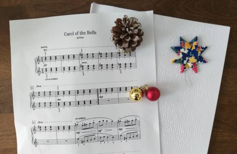 Zwei Notenblätter in Schwarzdruck und Braille von "Carol of the Bells" mit Tannenzapfen, Stern und Glöckchen