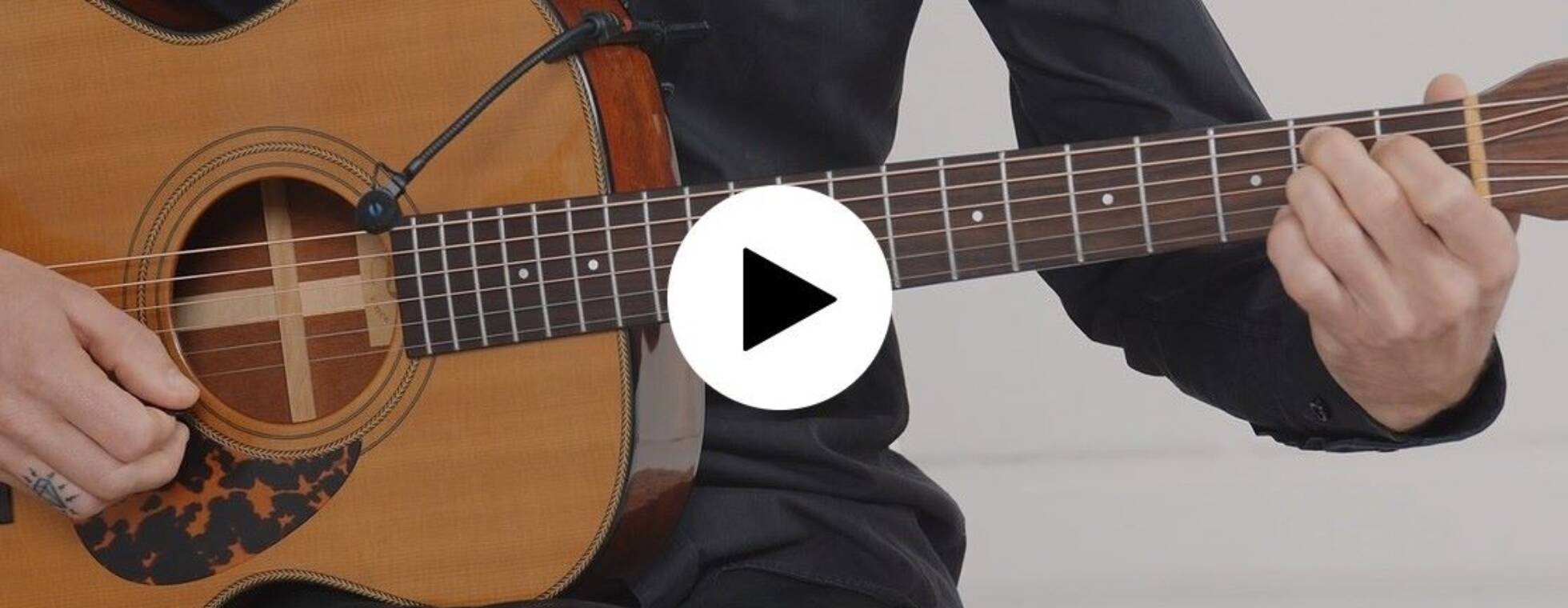 Screenshot des Gitarrenkurses. Im Bildausschnitt eine Gitarre, die gespielt wird und der Play-button