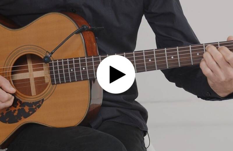 Screenshot des Gitarrenkurses. Im Bildausschnitt eine Gitarre, die gespielt wird und der Play-button