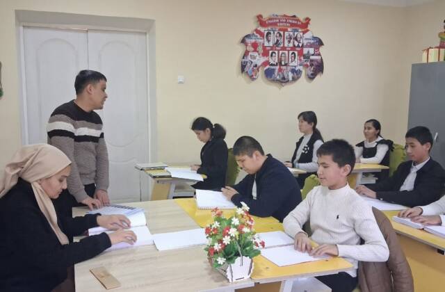 Eine Schulklasse sitzt im Klassenzimmer und liest Bücher mit den Händen.