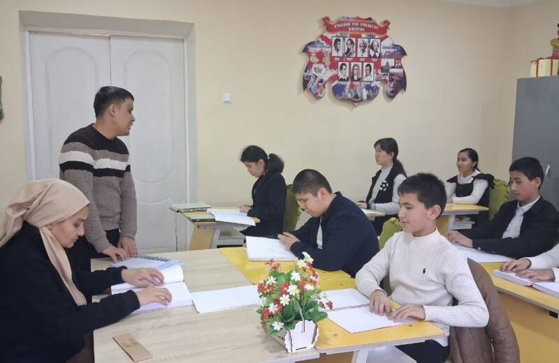 Eine Schulklasse sitzt im Klassenzimmer und liest Bücher mit den Händen.