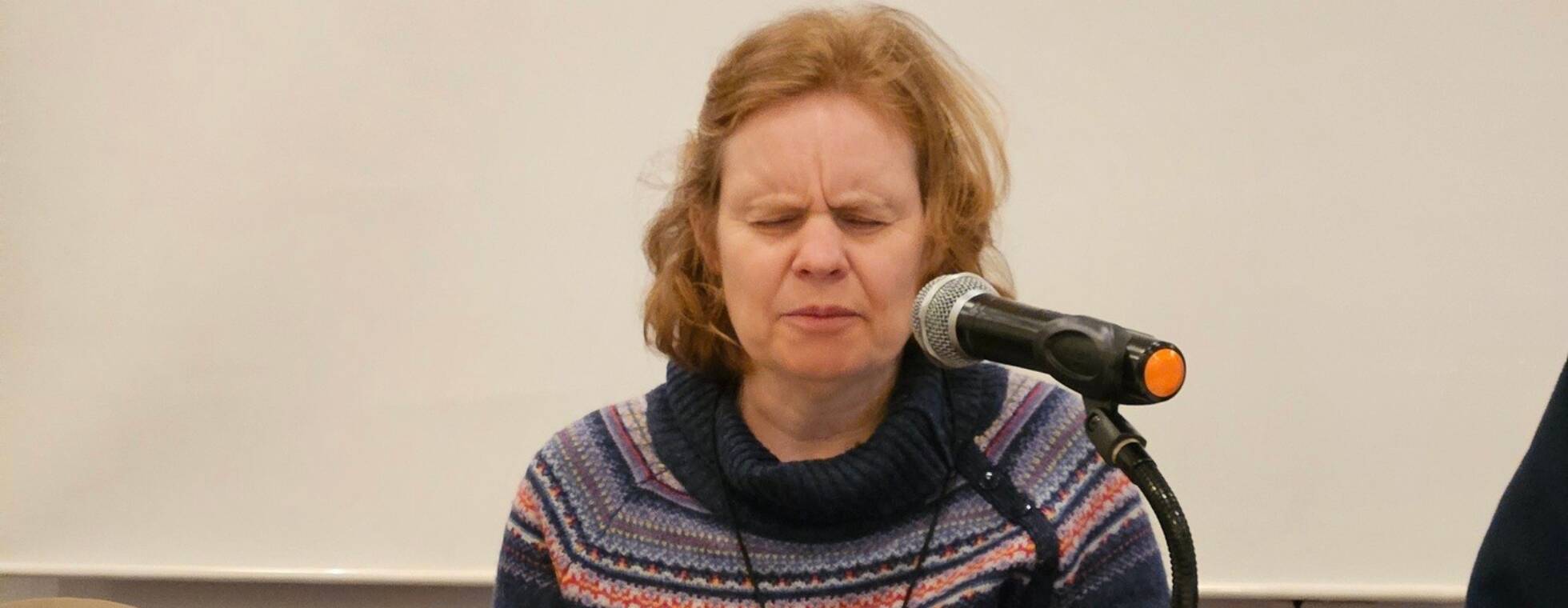 Vorstandsmitglied Anja Lehmann sitzt vor Mikrofon und Braillezeile an einem Tisch.